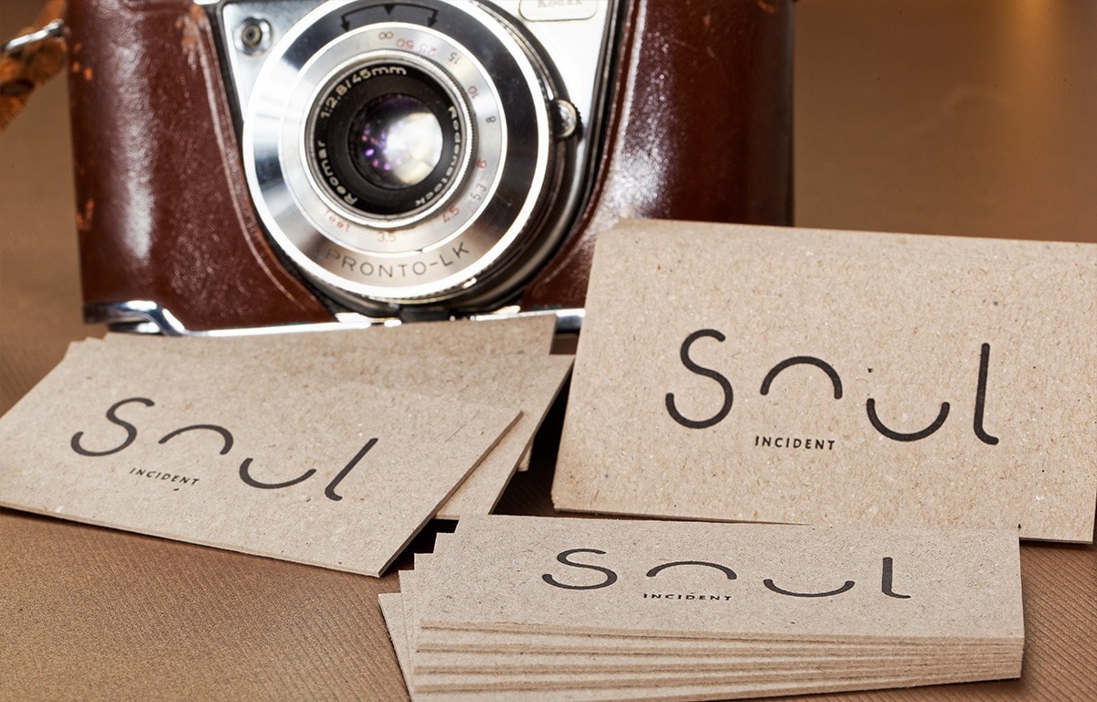 Natural recycled paperboard business cards arranged beside a vintage camera