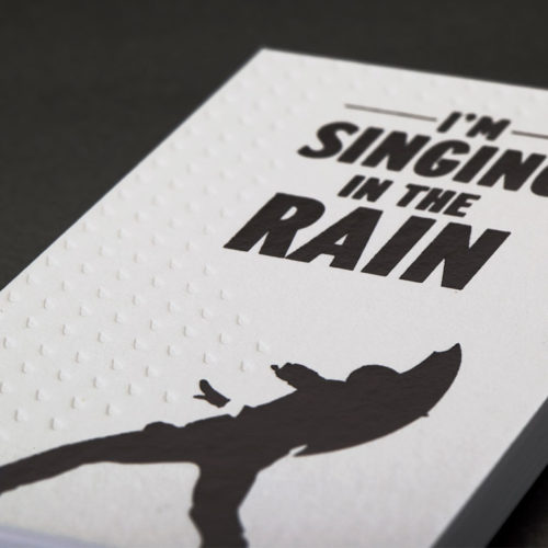 Business cards showing a man singing in the rain.