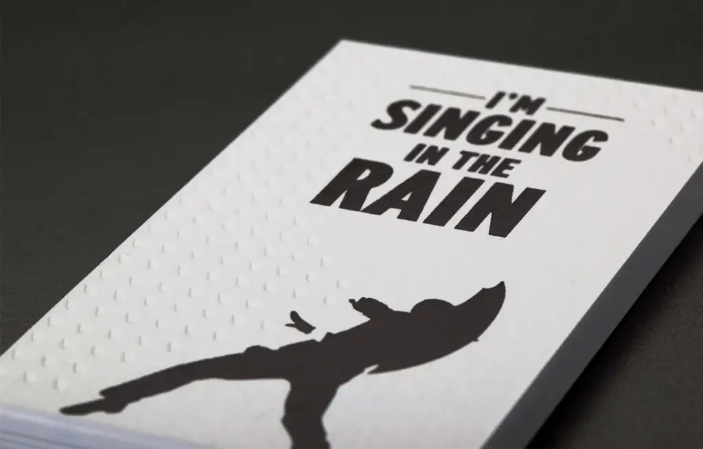 Business cards showing a man singing in the rain.