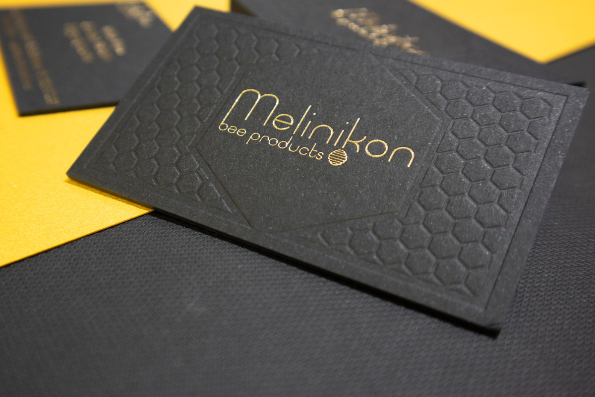 Angled Melinikon card showing gold foil and the depth of the blind pattern