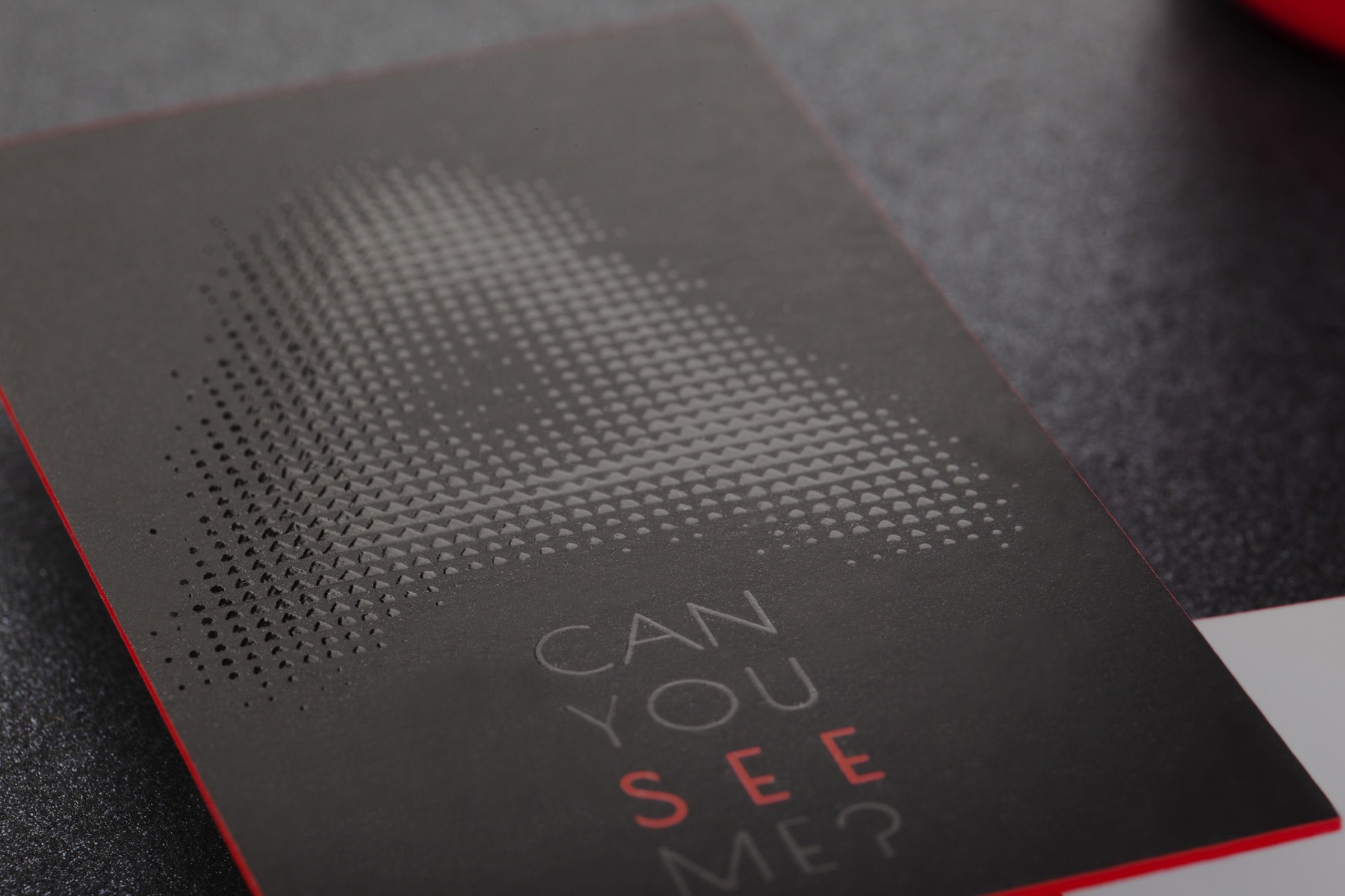 Black business card combining Spot UV matt lamination and a red painted edge